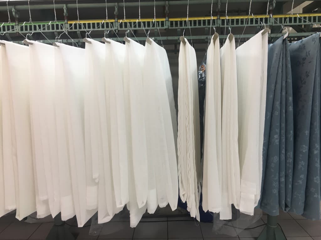 Rideaux nettoyés suspendus dans l’atelier après un sinistre — Pressing Vite Propre Bordeaux